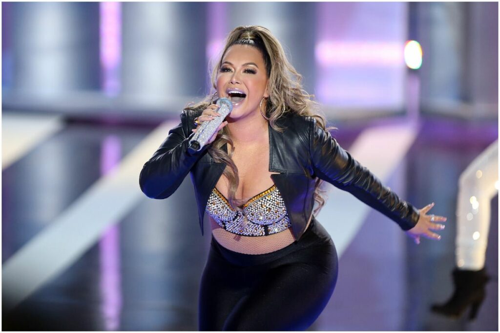 chiquis rivera holding a microphone and singing on stage