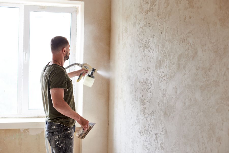 man drywalling and skim coating to get a smooth surface