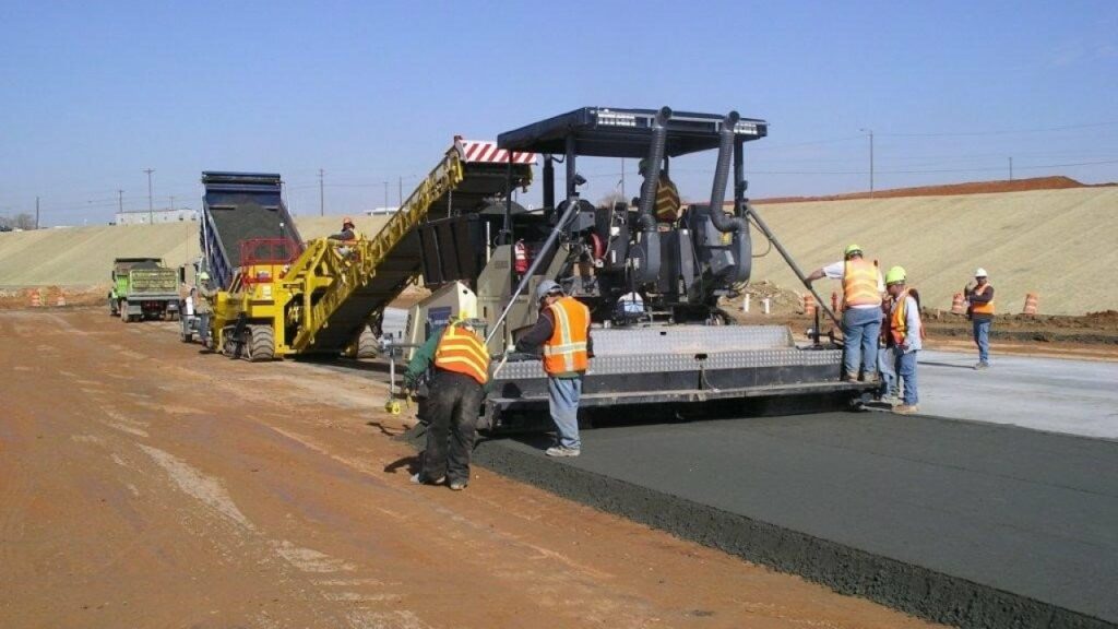 workers using a roller to compact on road construction
