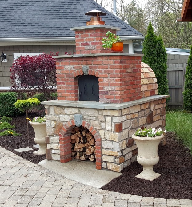 flower vases kept beside an outdoor fireplace with pizza oven