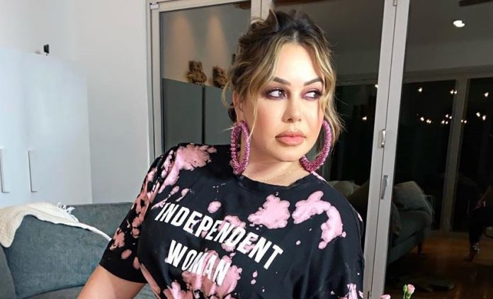 chiquis rivera on pink earing and staring outside 