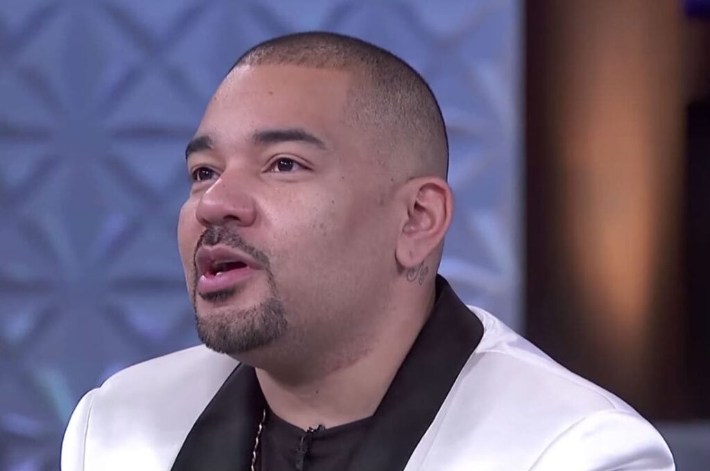 DJ Envy on a white jacket and speaking to the audience