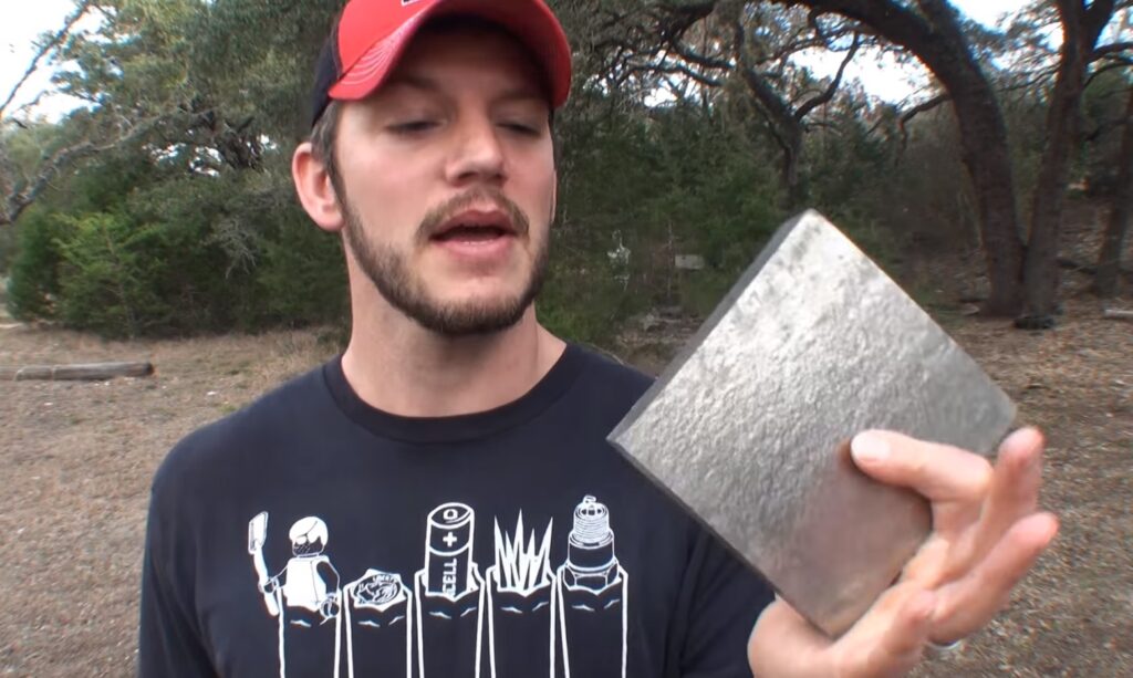 man holding a squared piece of titanium