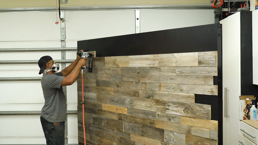 man using a drilling machine to build a pallet wall