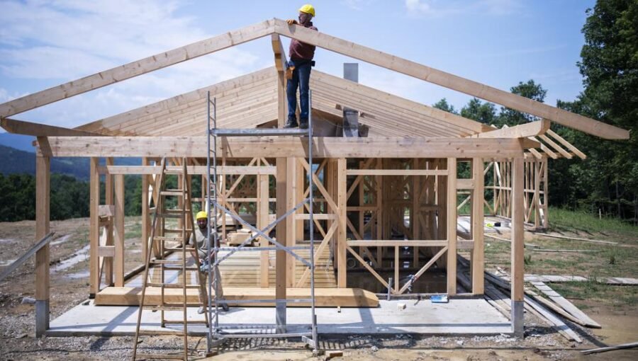 workers on site construction a house with wooden materials