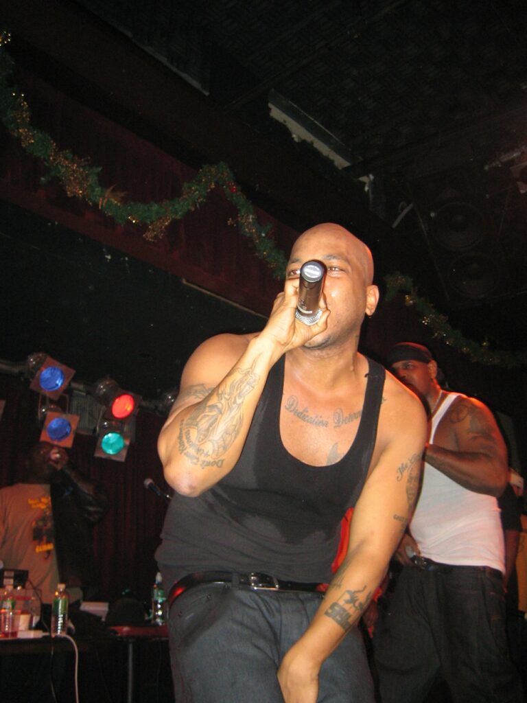 Styles P holding a microphone while performing on stage